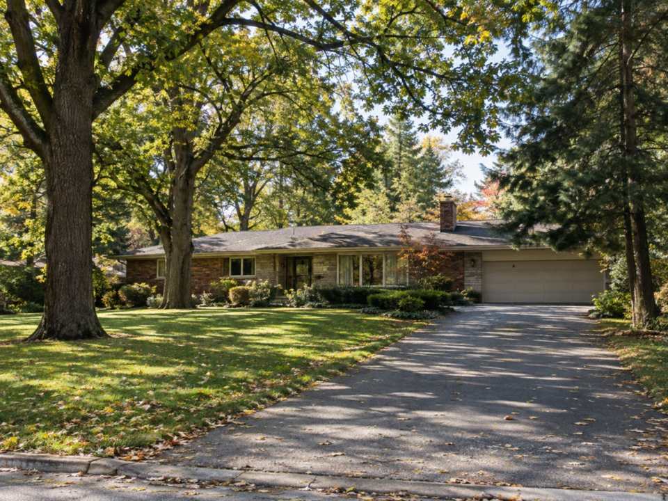 A 1960s ranch bungalow on a wide lot under tall oak and pine trees in Lorne Park